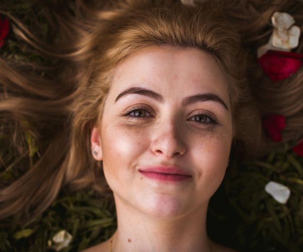 Person smiling peacefully outdoors, embodying a sense of well-being.